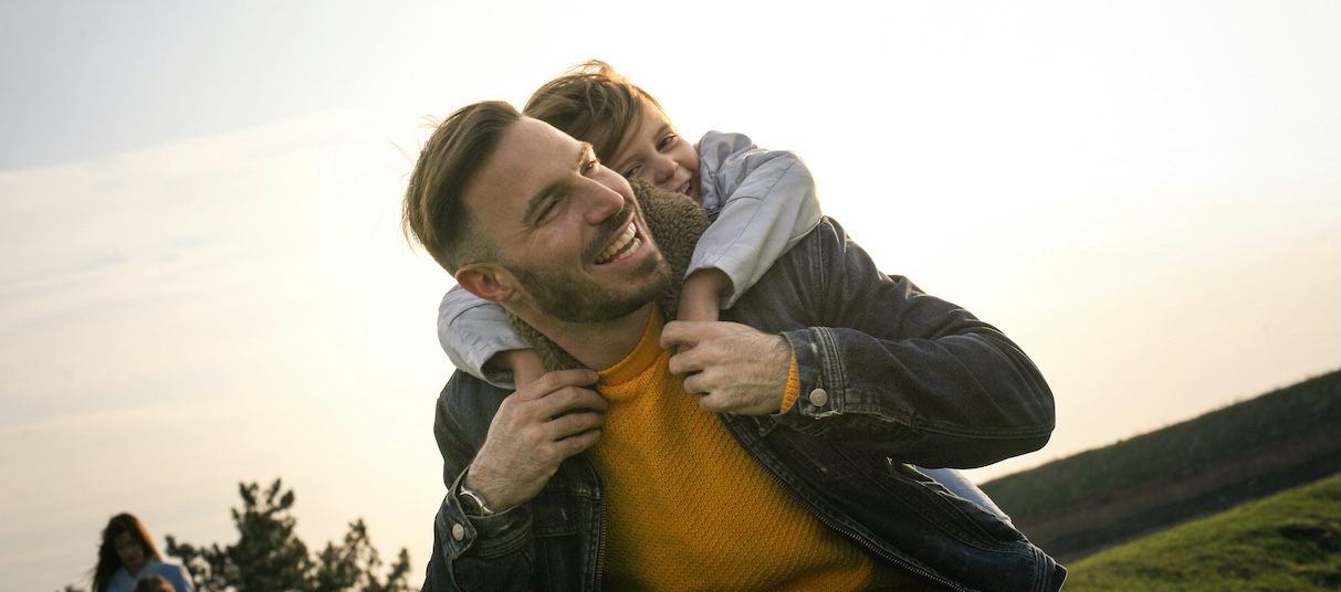 Father with son on his back enjoying time outside in an open field