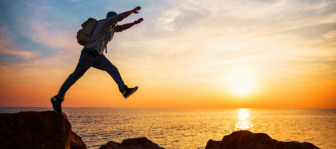 Man jumping from one rock to another along the coastline