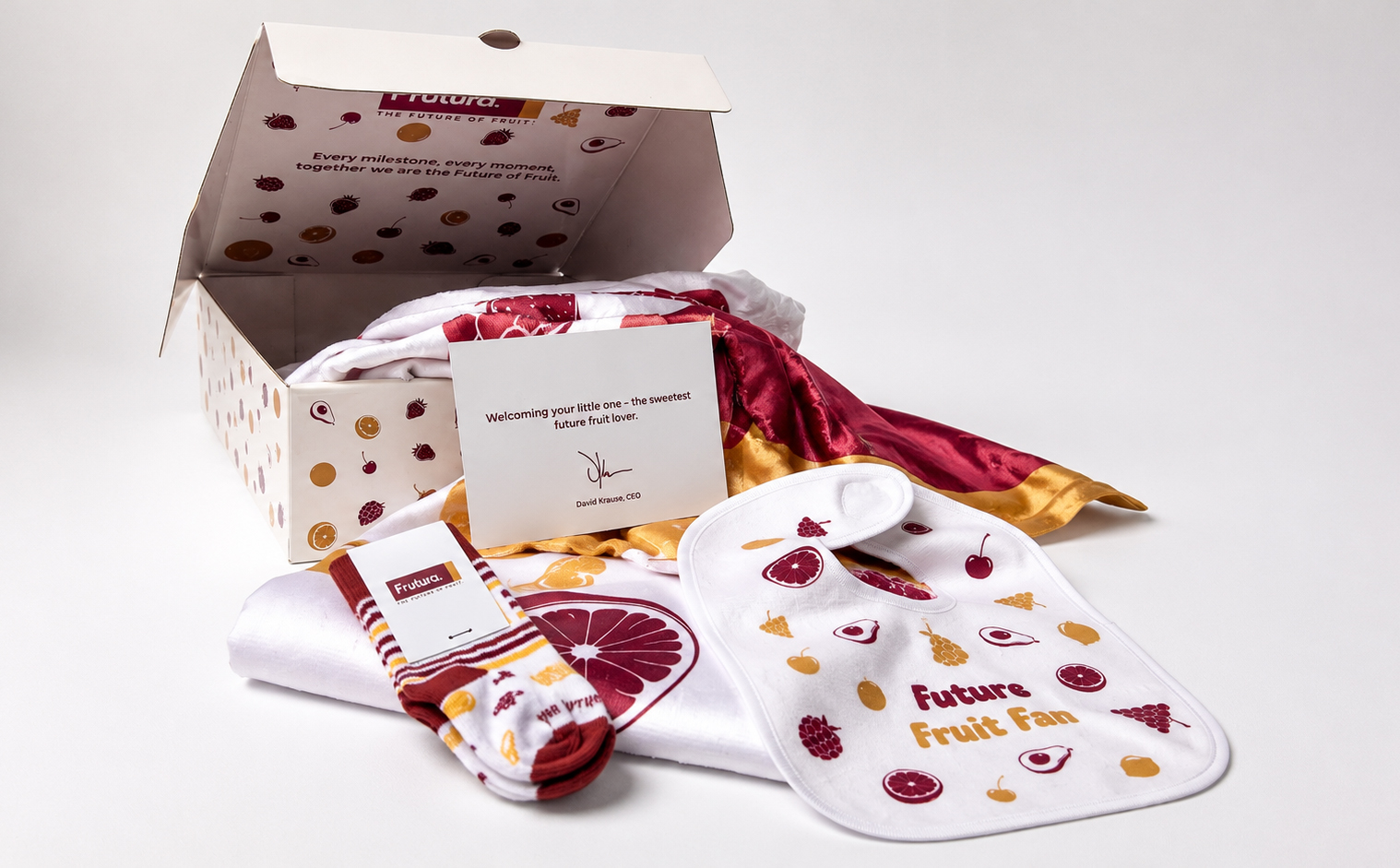 Frutura new-baby gift box with fruit-print packaging, a welcome card, blanket, bib, and socks