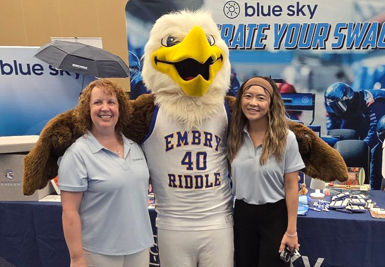 Two Blue Sky team members posing with the Embry-Riddle eagle mascot at a Blue Sky event booth