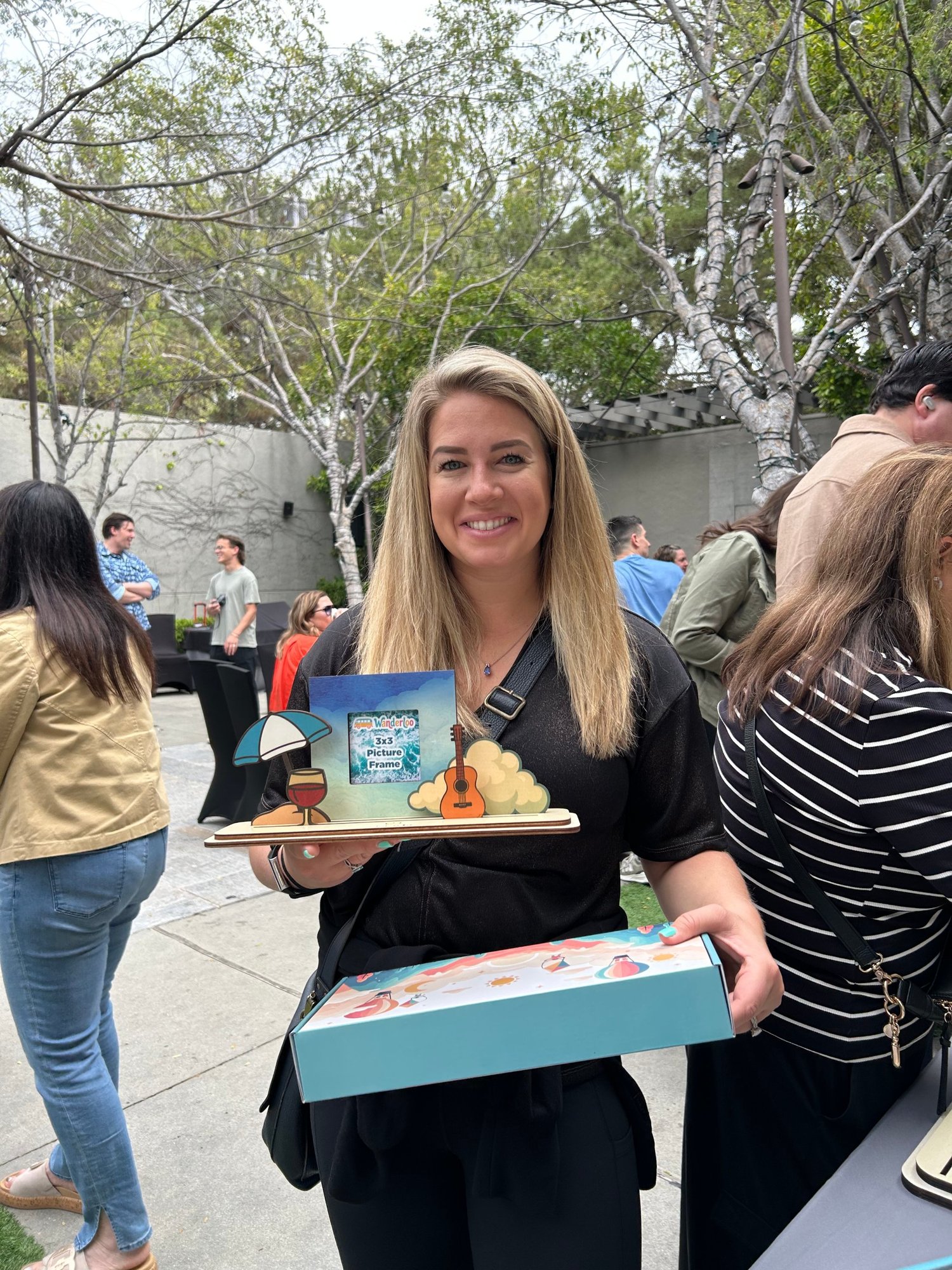 Smiling guest holding her finished Wanderloo frame and its open gift box