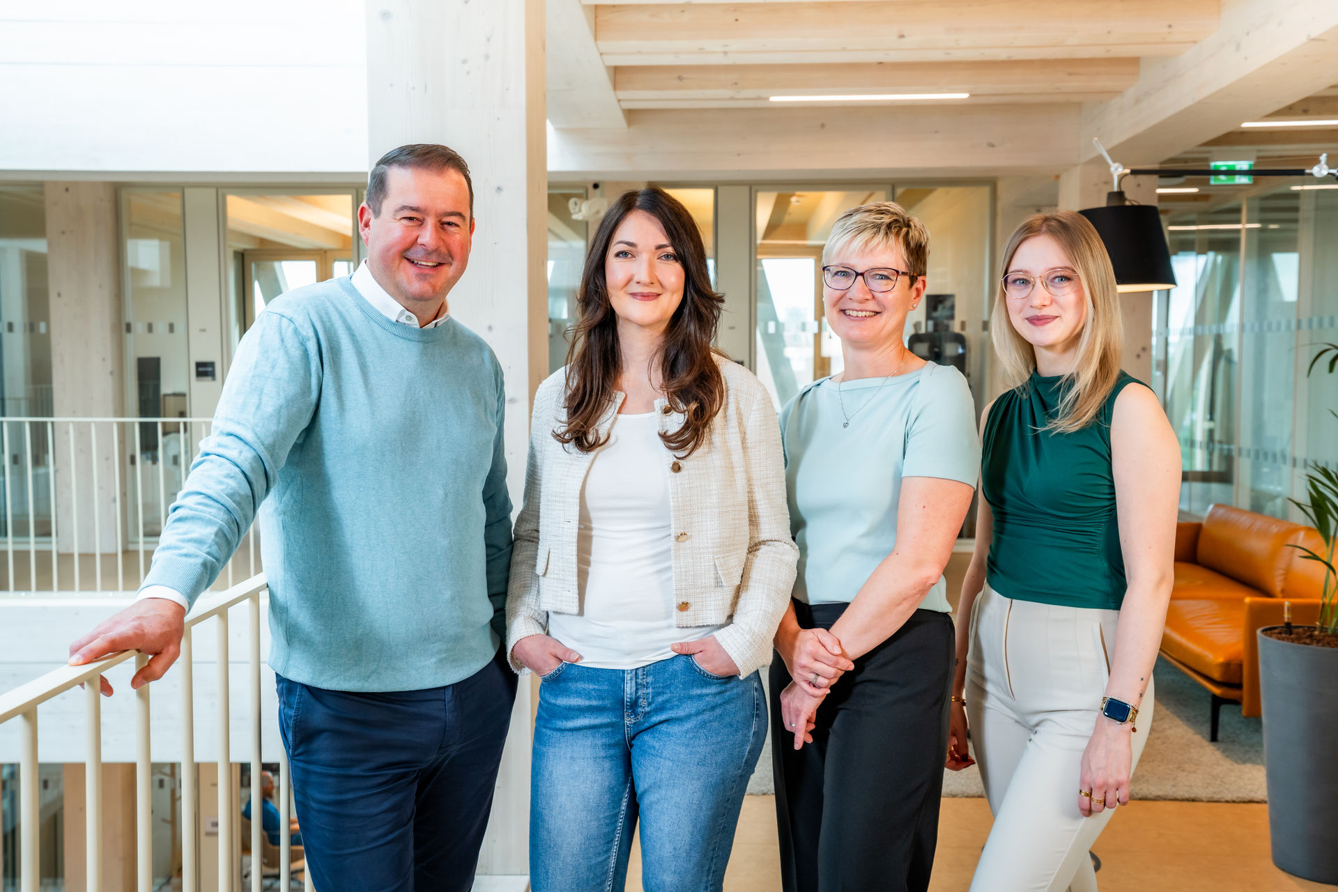 Team der b+ GmbH mit Geschäftsführer und drei Mitarbeiterinnen im modernen Büro.