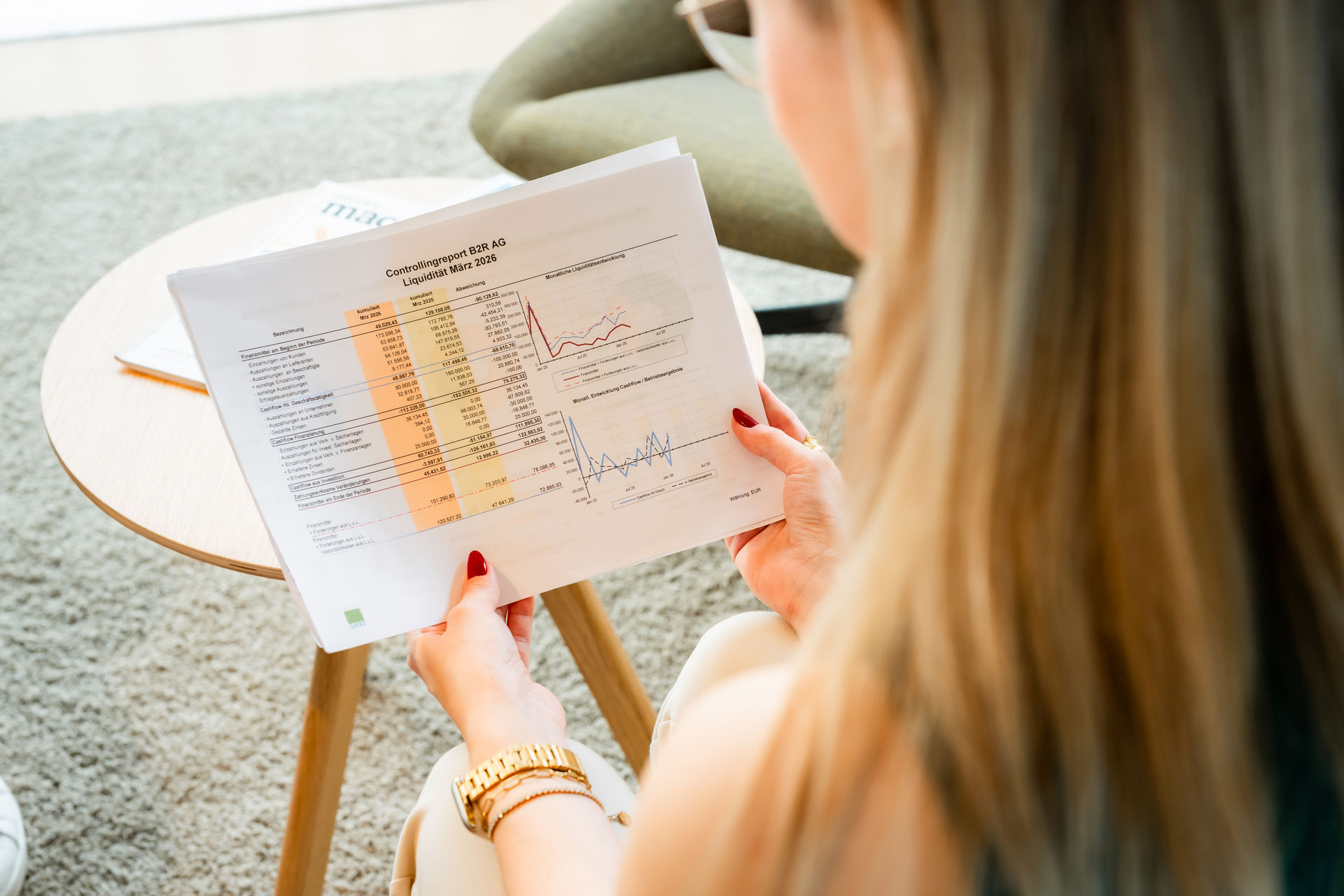 Frau liest einen gedruckten Finanzbericht mit Kennzahlen und Diagrammen.