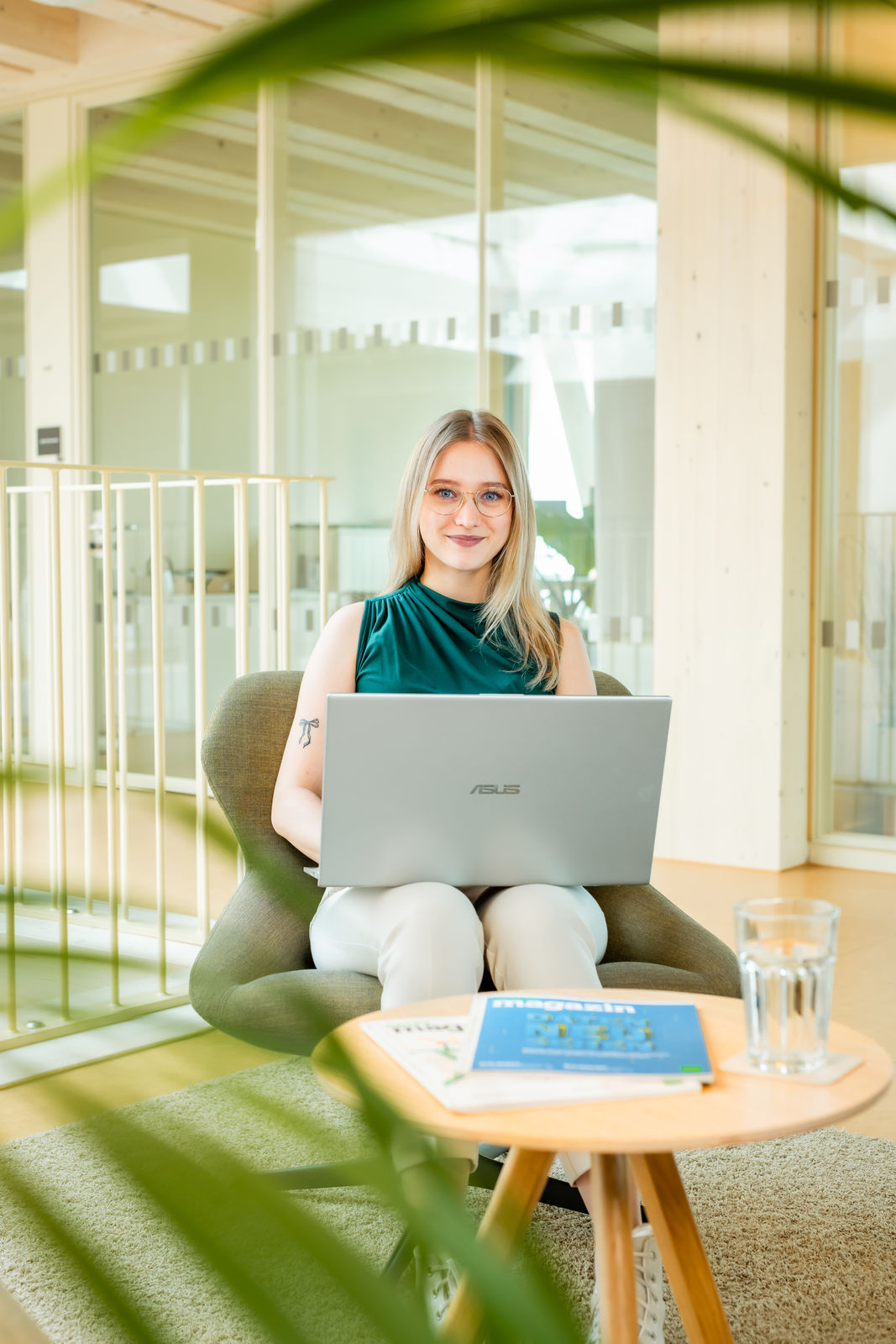 Junge Frau sitzt mit Laptop in modernem Büro für die digitale Jahresabschluss-Vorbereitung.
