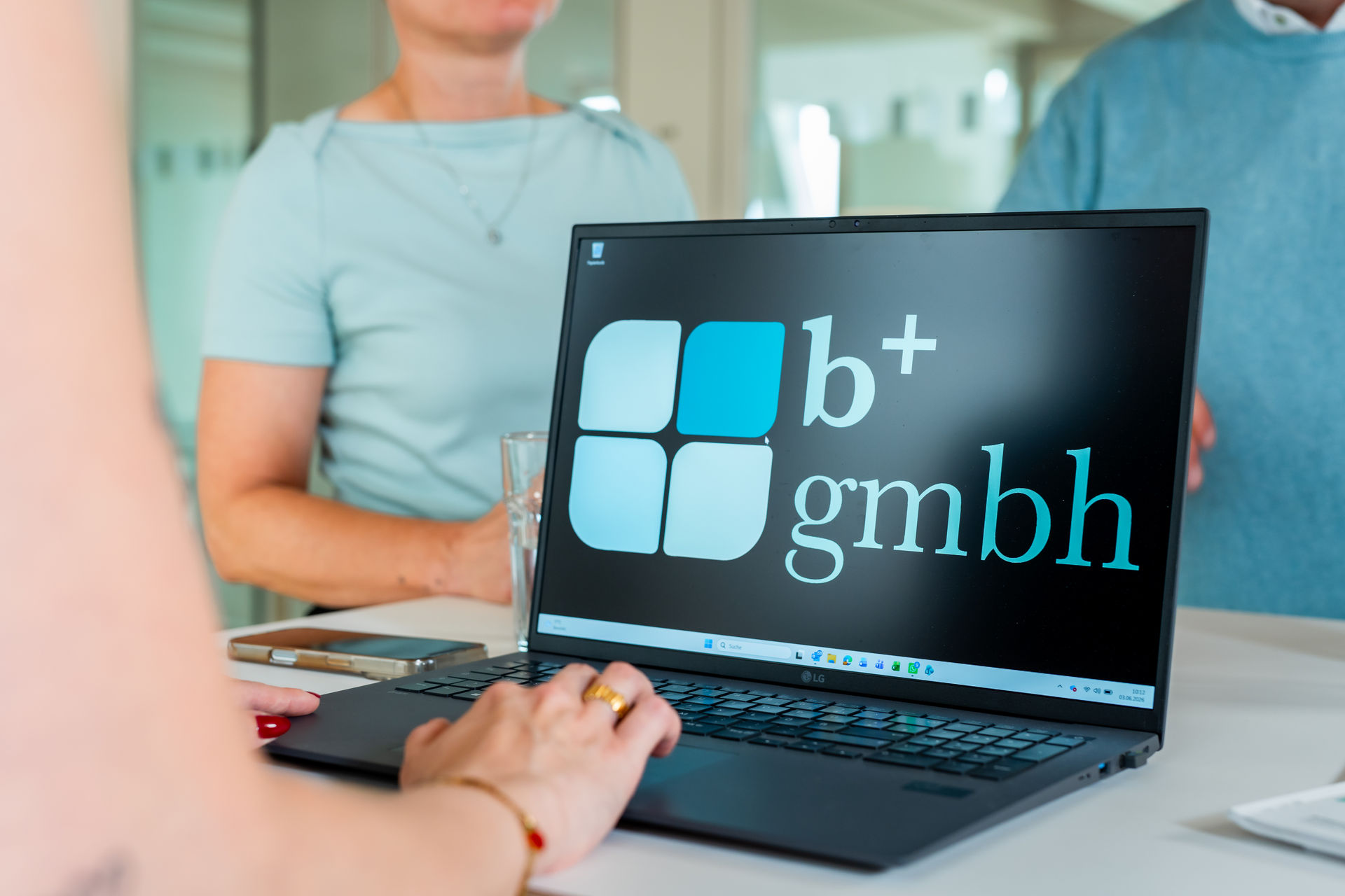 Nahaufnahme: Hände am Laptop mit b+ GmbH Logo bei der digitalen Rechnungsverarbeitung.