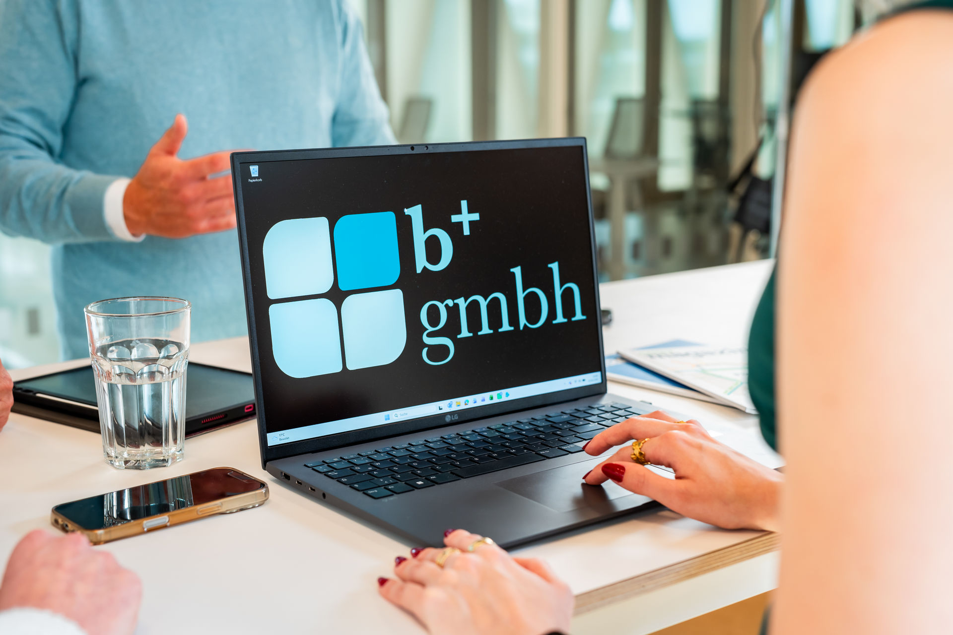 Laptop mit b+ GmbH Logo auf dem Bildschirm, geöffnet in digitaler Buchhaltungssoftware.