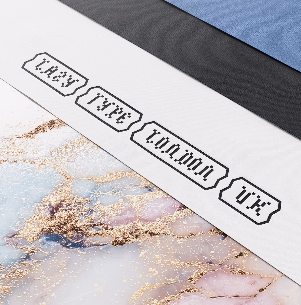 A LazyType Mockup showing embossed text on white paper with pixel font reading 'lazy Type London UK' over a marble surface.