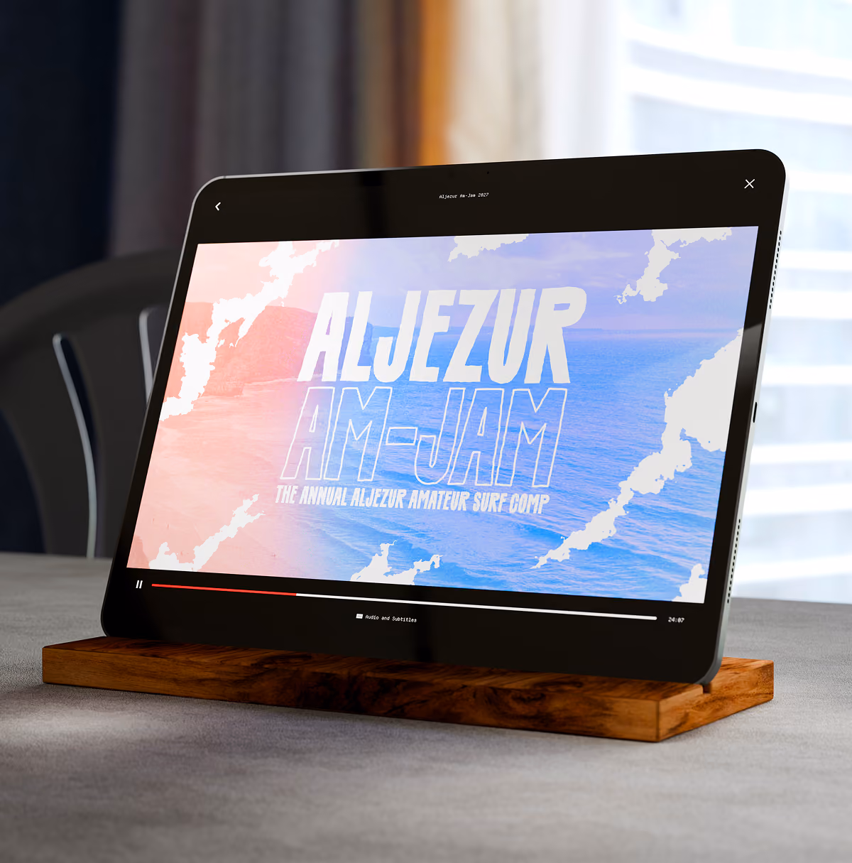 A LazyType Mockup showing an iPad on wooden stand showing video titled Aljezur Am-Jam, an annual amateur surfing competition.