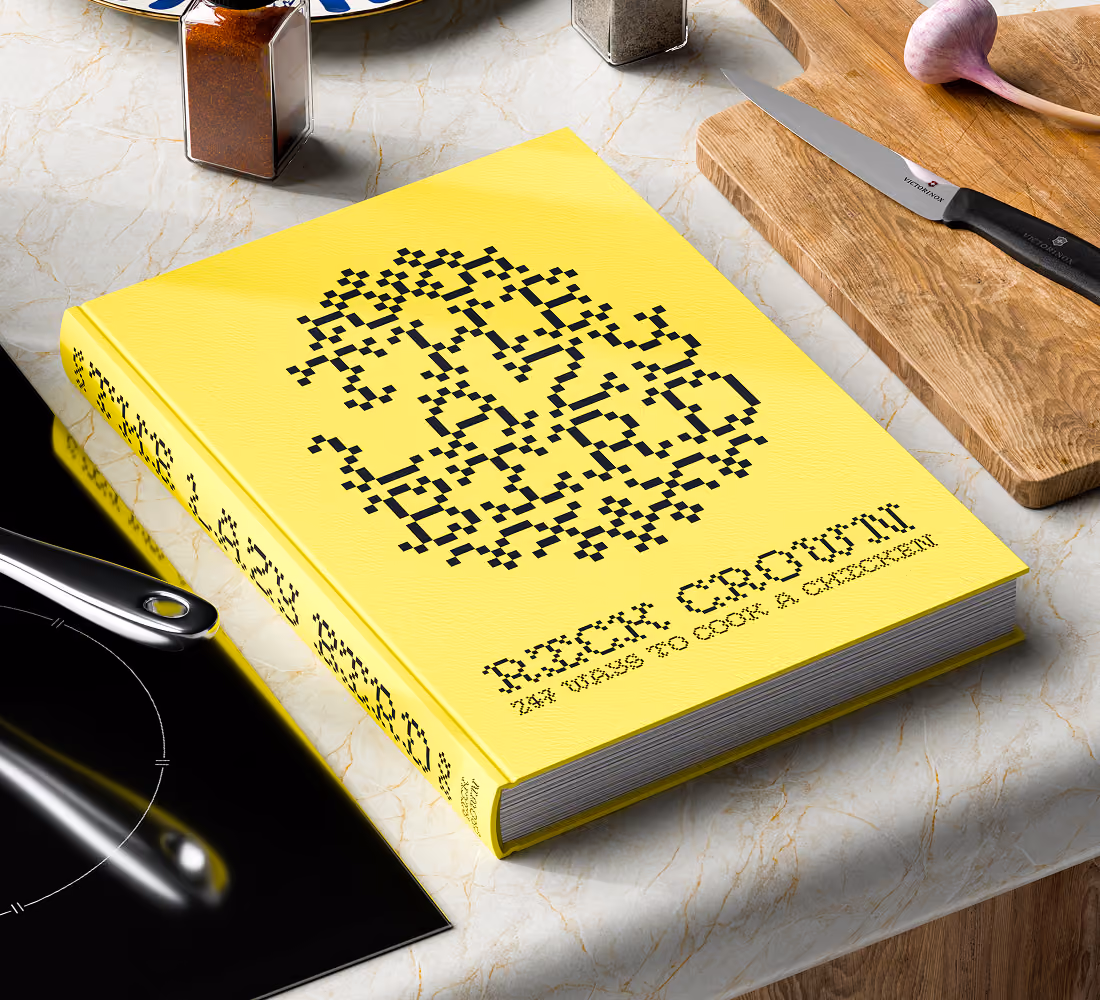 A LazyType Mockup showing a yellow cookbook titled 'The Lazy Bird: 24 Ways to Cook a Chicken by Rick Crown' on a marble kitchen surface.