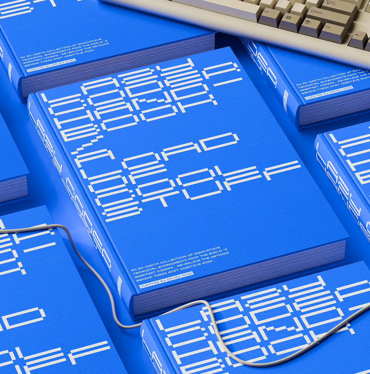 A LazyType Mockup showing blue books titled Lazy Coder Handbook with blocky pixelated white text arranged on a blue surface with a keyboard and a wire.