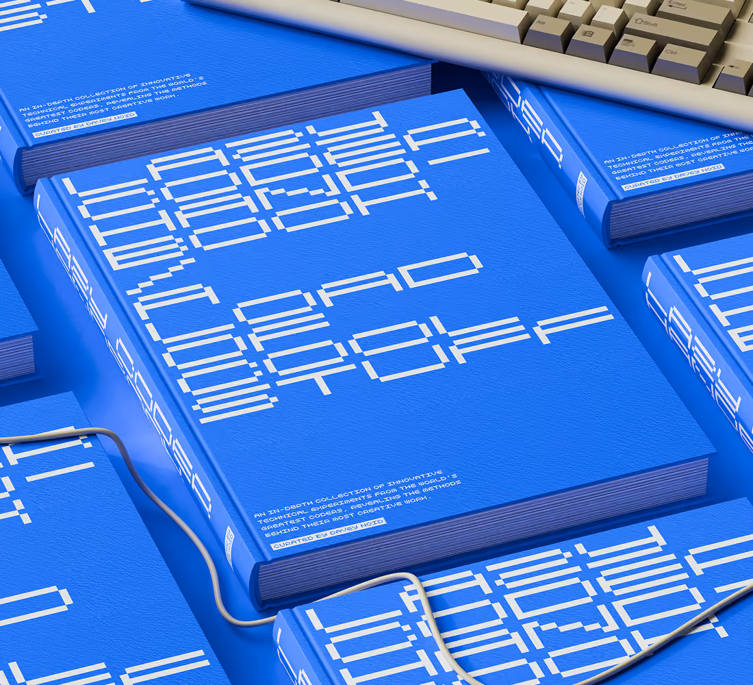 A LazyType Mockup showing blue books titled Lazy Coder Handbook with blocky pixelated white text arranged on a blue surface with a keyboard and a wire.