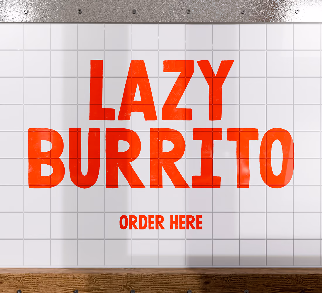 A LazyType Mockup showing a Burrito logo in red text reading 'LAZY BURRITO' and 'ORDER HERE' on a white tiled wall above a wooden surface.