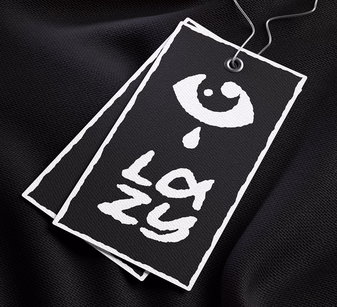 A LazyType Mockup with black fabric with black tags roughly outlined in white, featuring a stylised eye and text 'Lazy'.