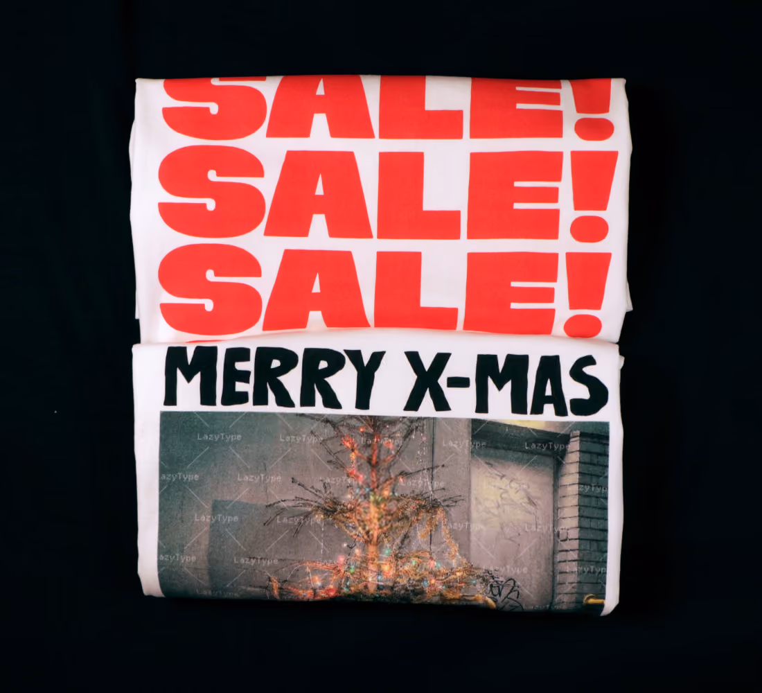 LazyType merch showing two folded t-shirts. One with red text reading "SALE! SALE! SALE!" and the other with black text reading "MERRY X-MAS".