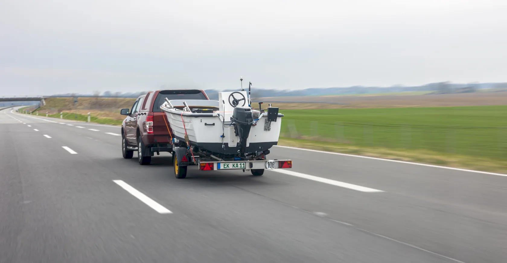 Pickup truck towing a boat trailer on the road