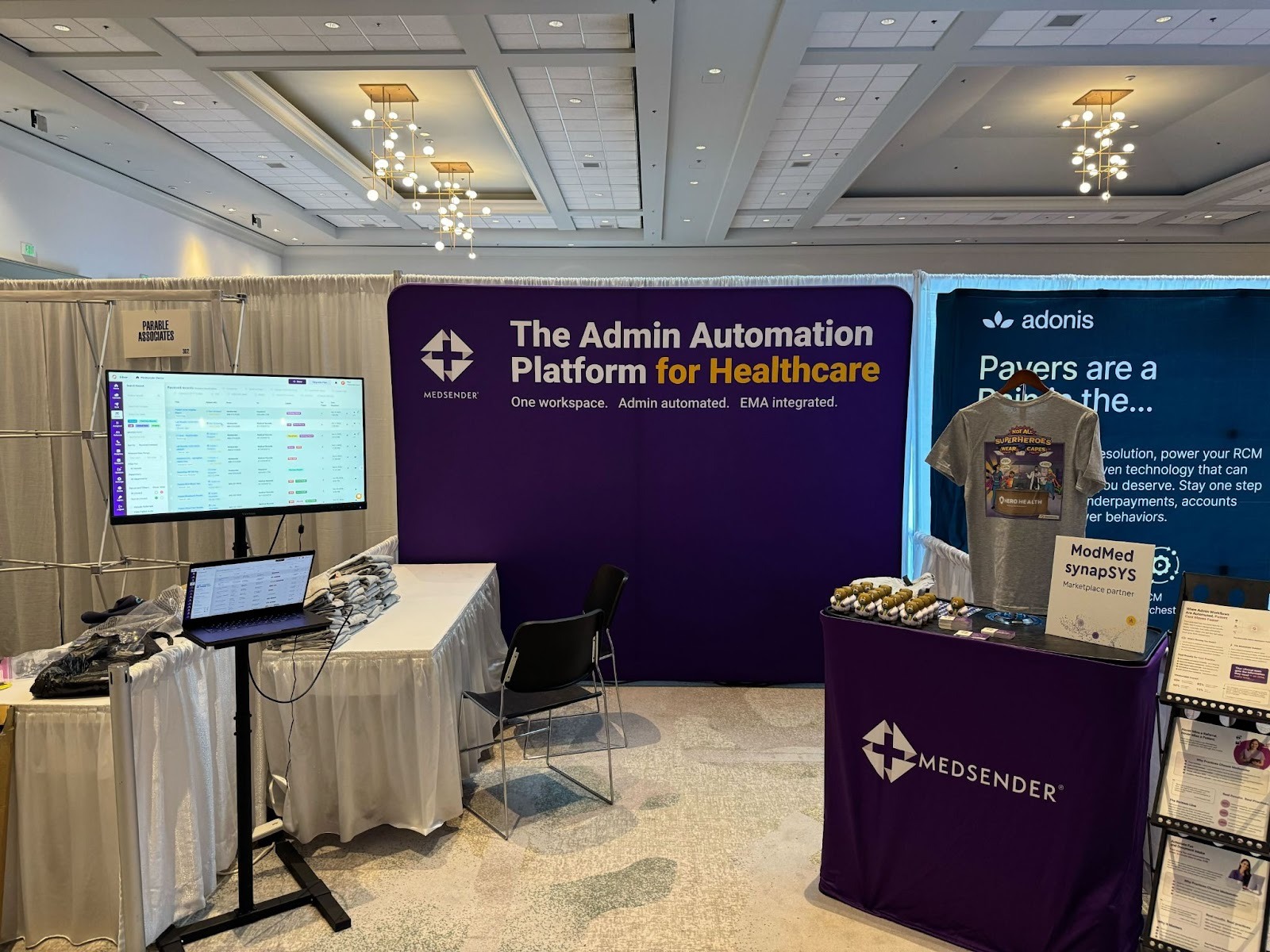 Medsender's booth at MOMENTUM 2025 with the Admin Automation Platform for Healthcare backdrop, live demo screens, and branded table