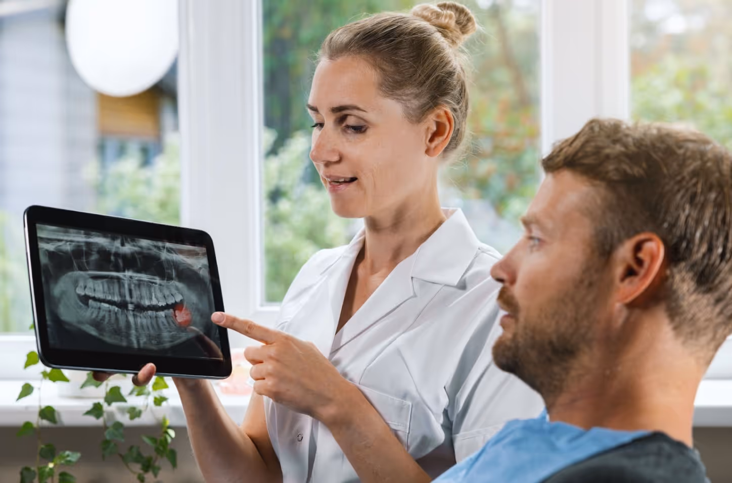 Dentist showing a patient their dental X-ray on a tablet during a consultation