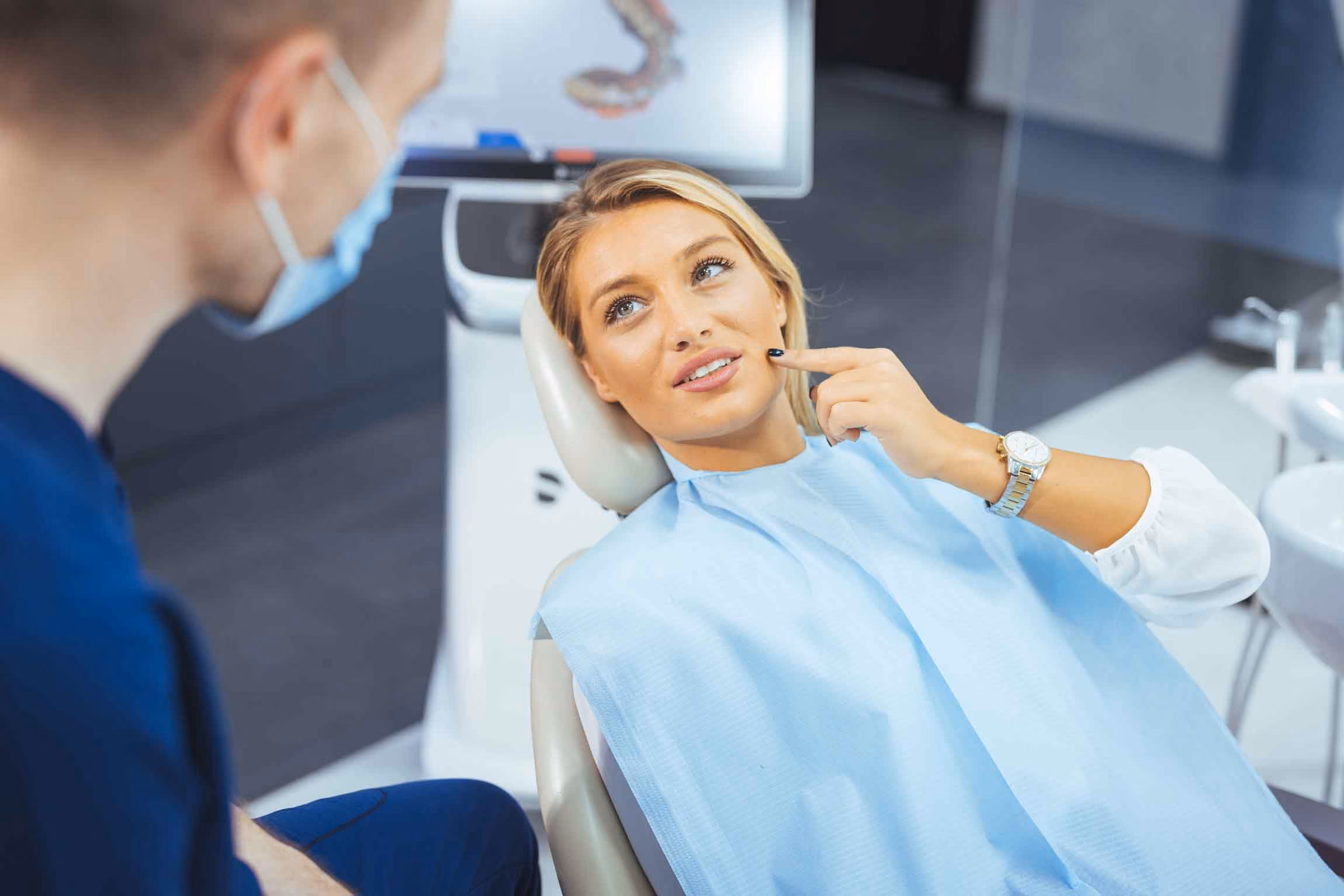 Woman pointing to her cheek during a dental exam