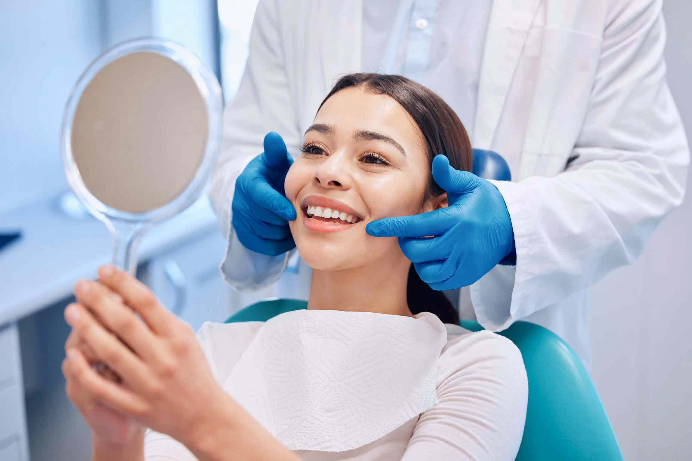 Woman smiling into a mirror after a dental exam