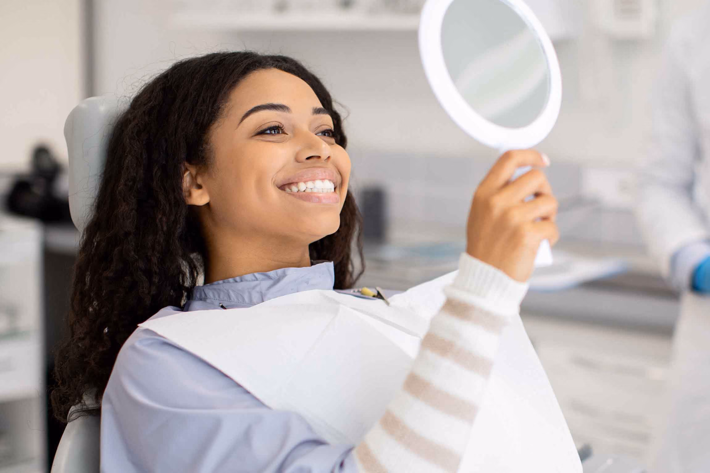 Woman smiling while holding a mirror.