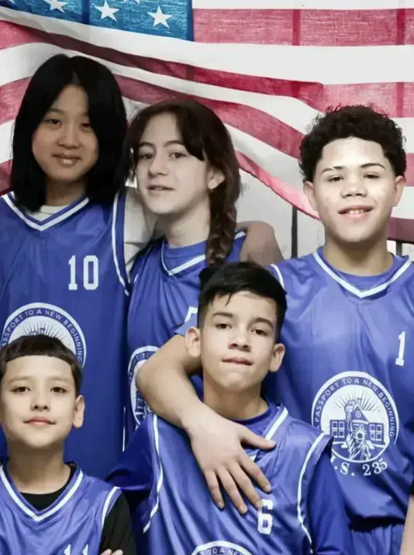 Five PS 235 students in blue team jerseys in front of American flag