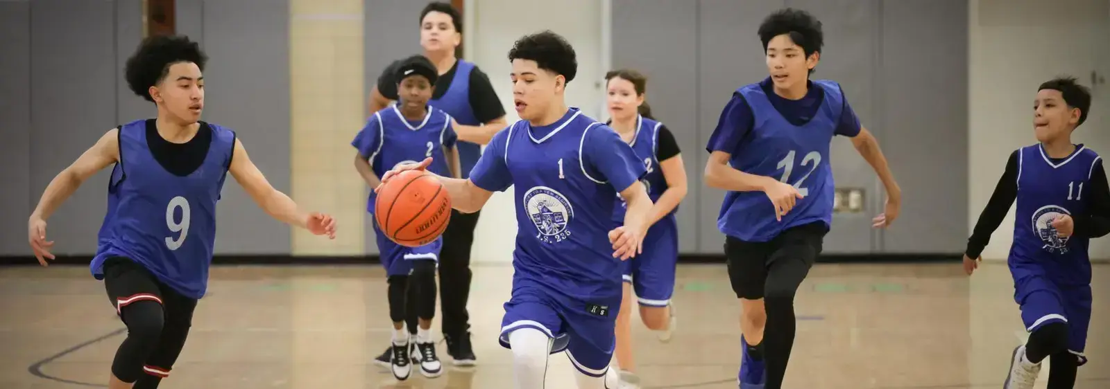 Students playing basketball during an indoor school gym game