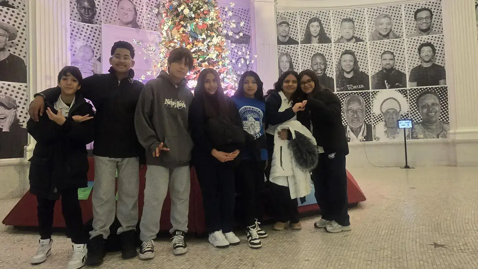 Students posing together in front of a decorated holiday tree
