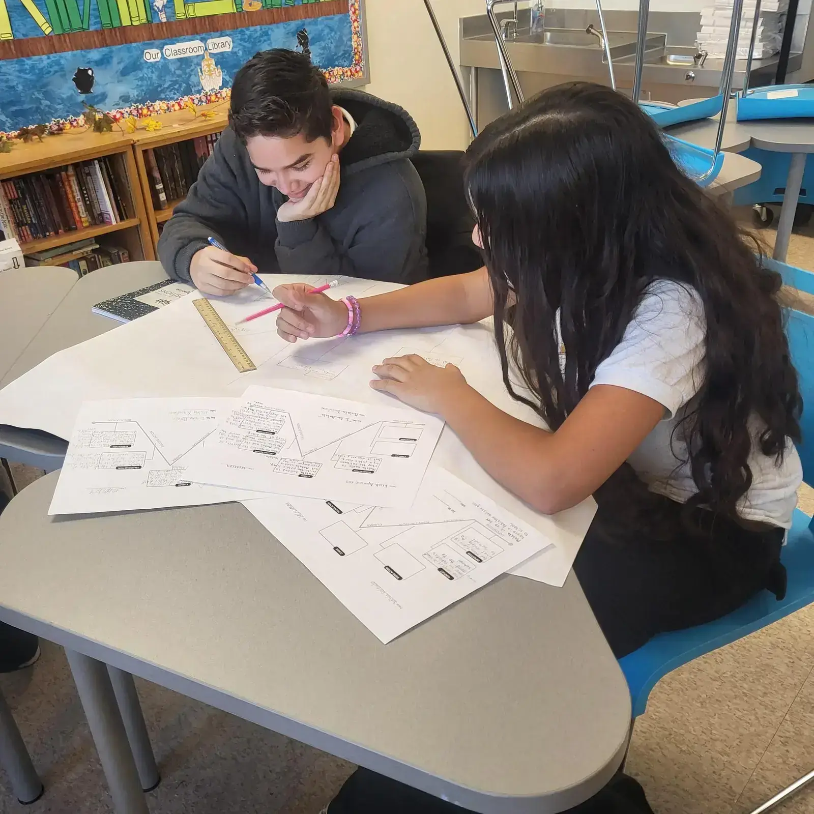 Two students collaborating on a diagram project at classroom table
