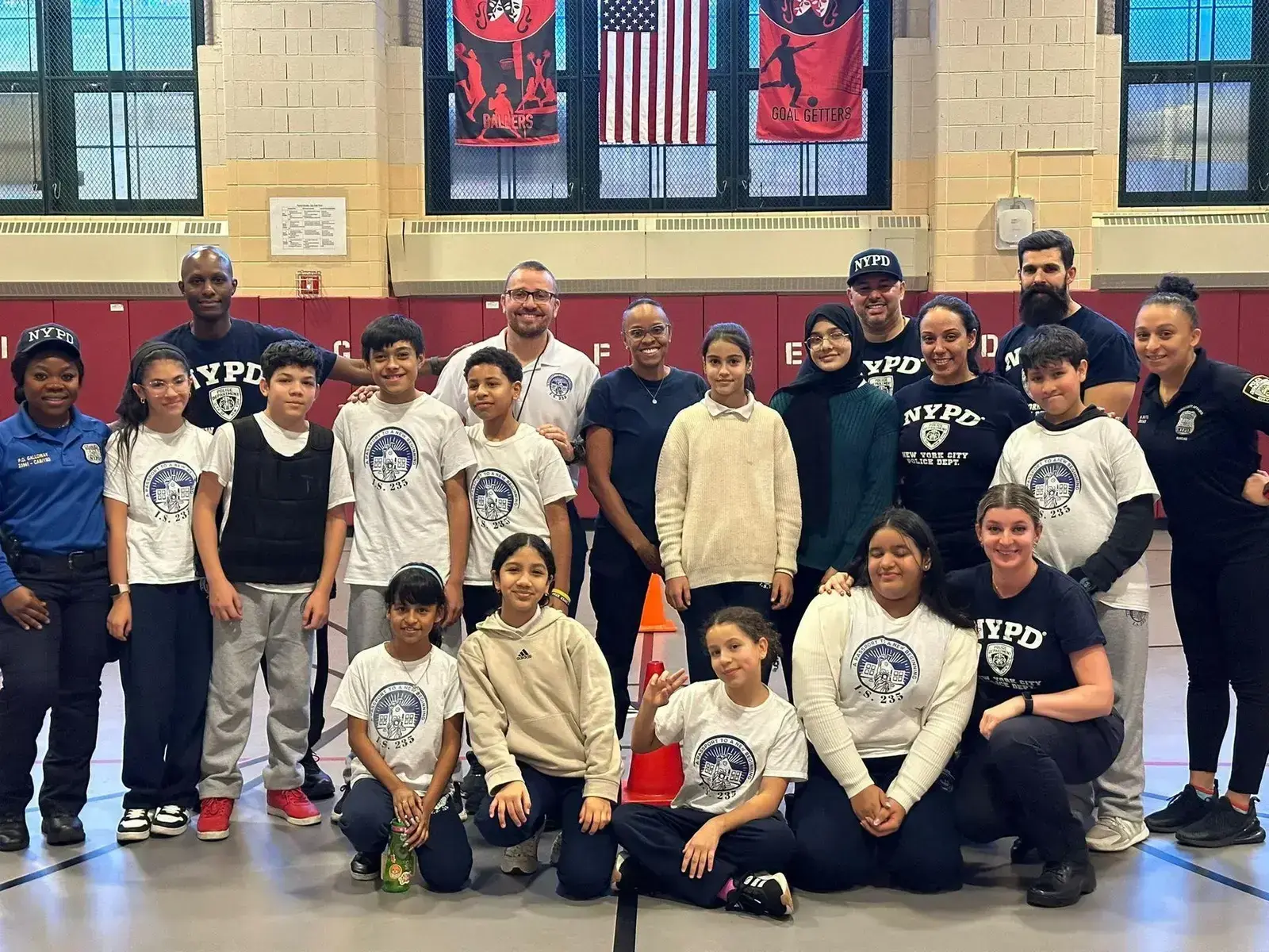 Students and NYPD officers pose together in school gymnasium