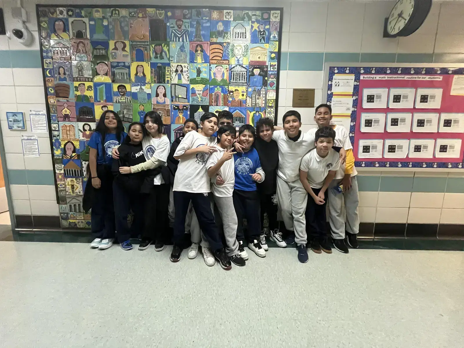 Students posing together in front of colorful hallway mural