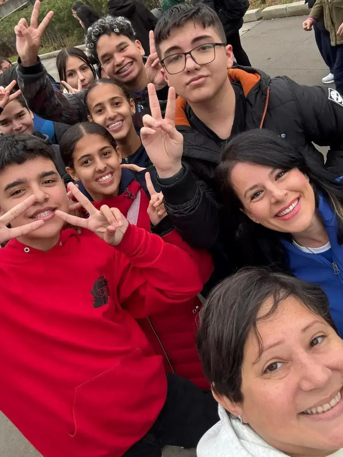 Students and teachers smiling together outdoors on a school trip