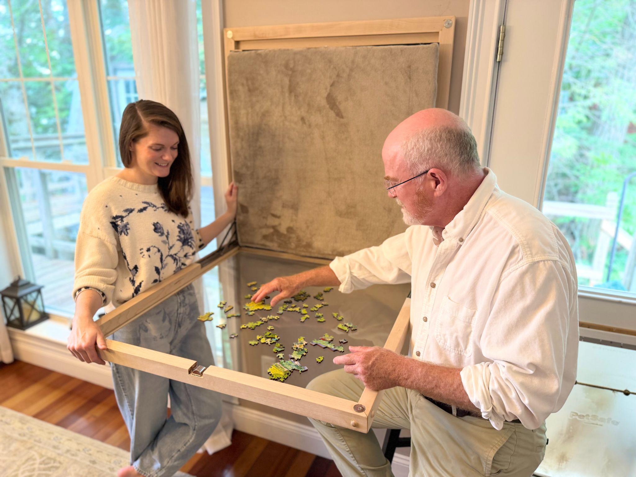 David and Madeline Branch opening a Puzzle Murphy prototype at home, with a jigsaw puzzle in progress inside.