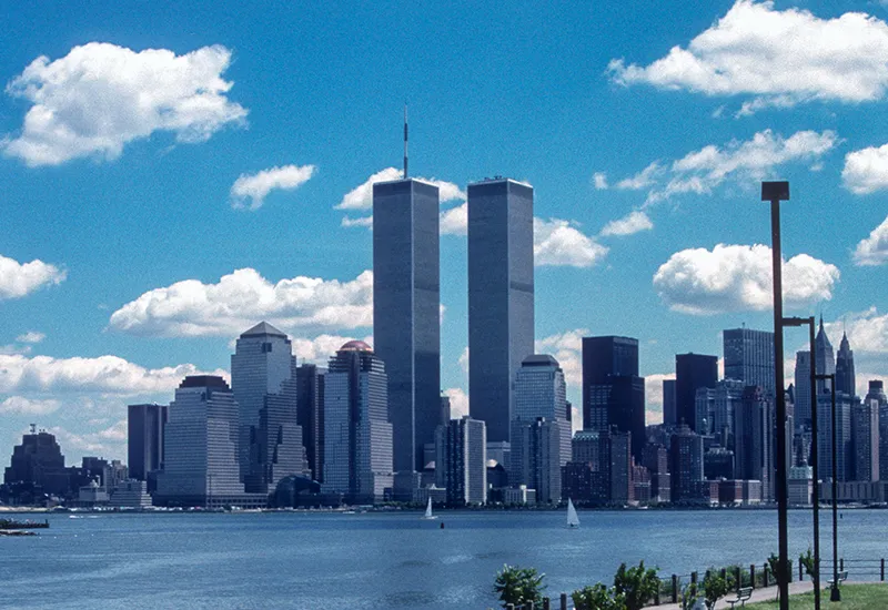 New York City skyline with the Twin Towers on a clear day with partly cloudy blue sky.