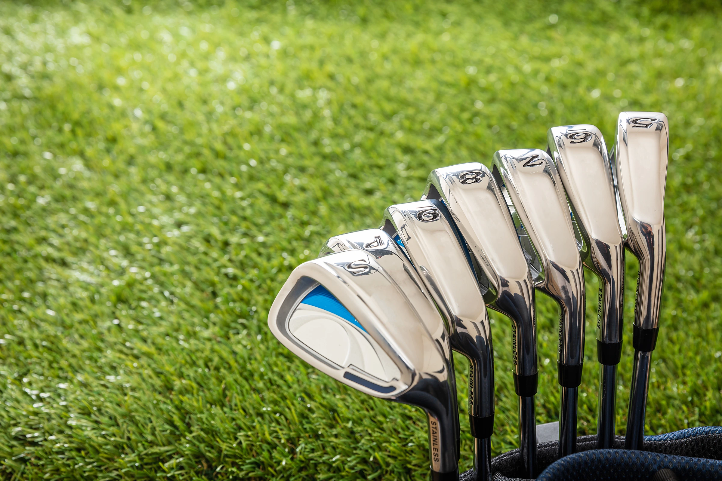 Set of golf irons laid on the grass