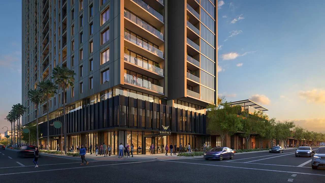 Sunset street view of Whitney high-rise with people walking and cars driving nearby.