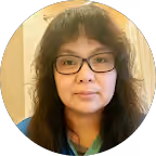 Woman with long dark hair, glasses, and a neutral expression, wearing a blue collared shirt.