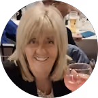 Smiling woman with blonde hair holding a glass of pink drink.