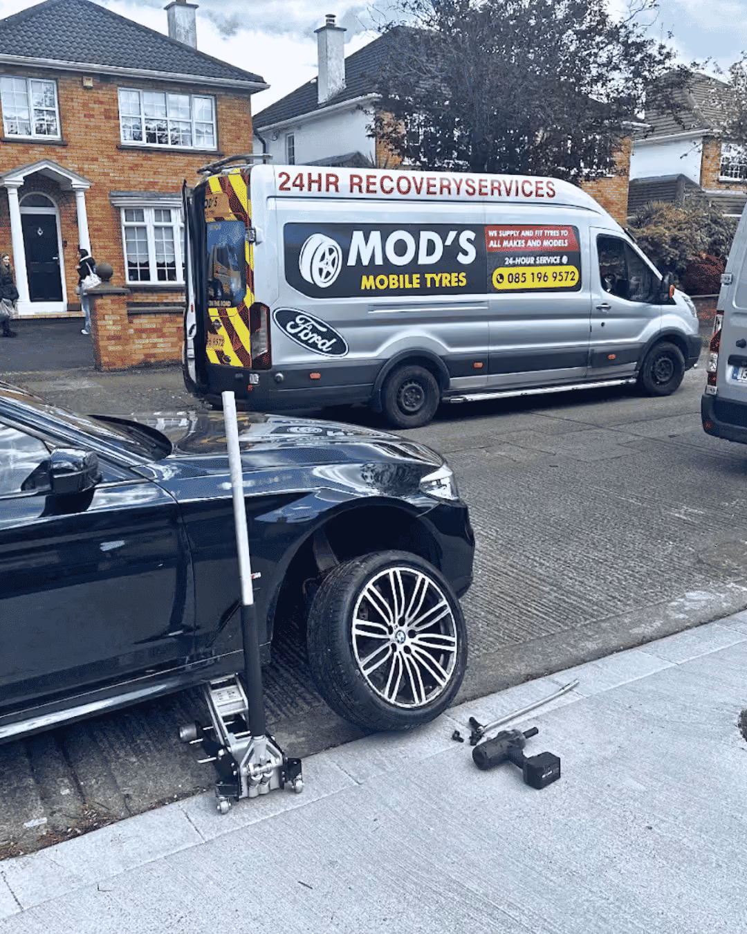 Mobile tire service van parked near a black car being serviced for a wheel change.