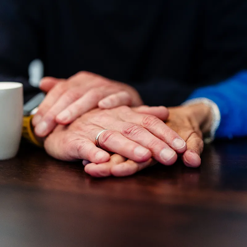 Twee handen rusten in elkaar op tafel tijdens de 8-weekse EFT-relatietraining van Voordeliefde