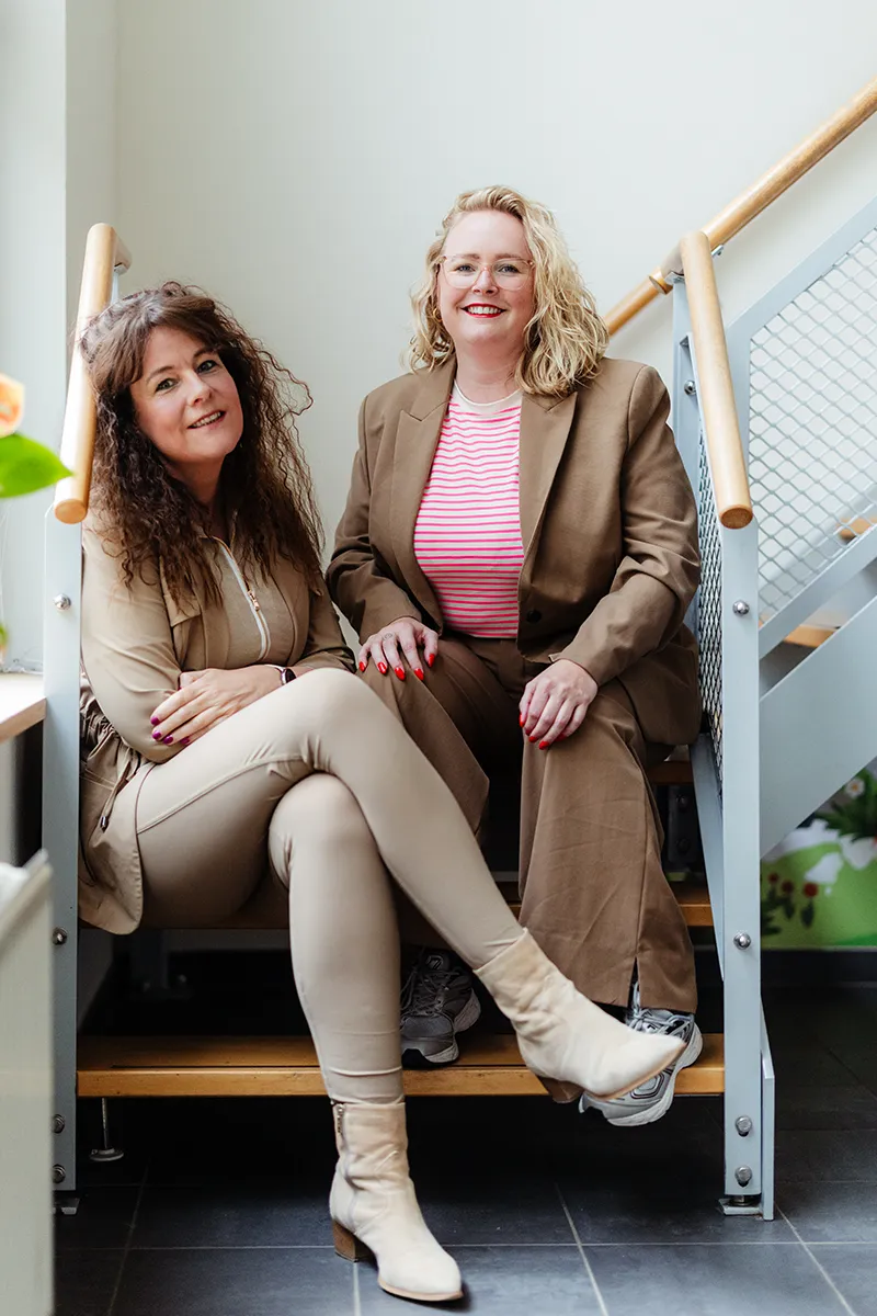 Relatiecounselors Carolien en Jolien zitten samen op de trap, de begeleiders van de 8-weekse EFT-relatietraining