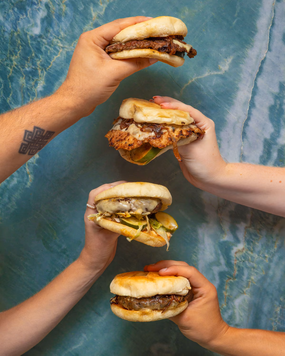 hands holding different types of burgers
