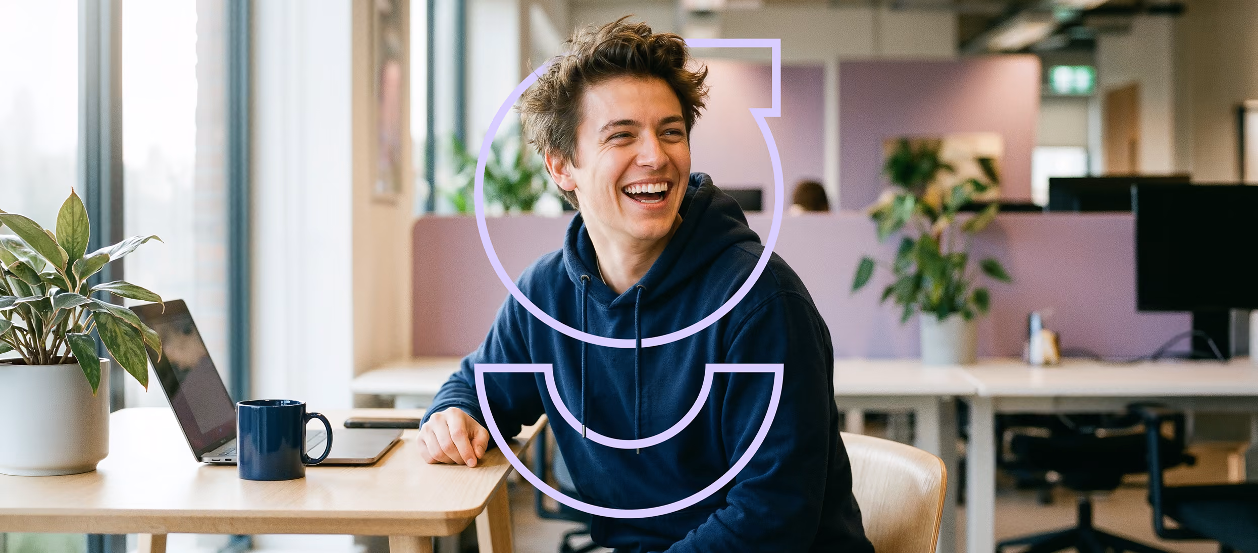Mitarbeiter im Büro mit gebrandetem gaavoo Hoodie und Kaffeetasse am Schreibtisch