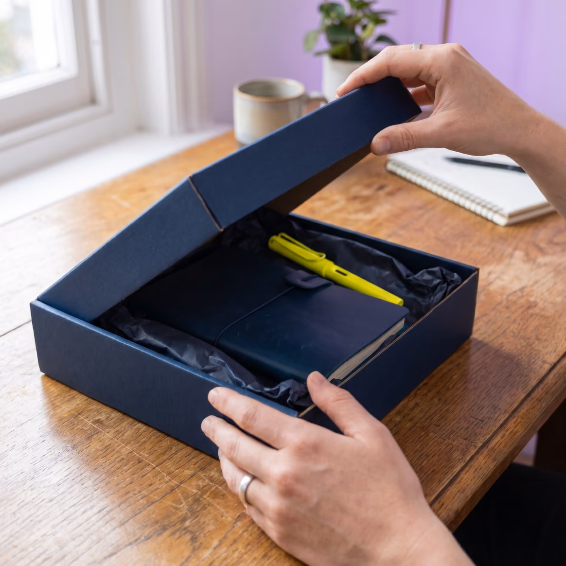 Haptisches Unboxing einer exklusiven Geschenkbox mit Notizbuch und Stift