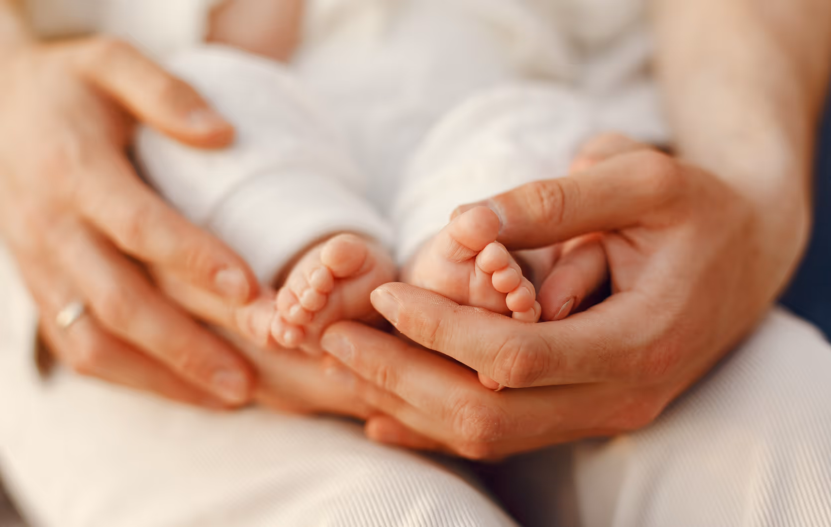 A parent's hands gently cradling a newborn's feet.