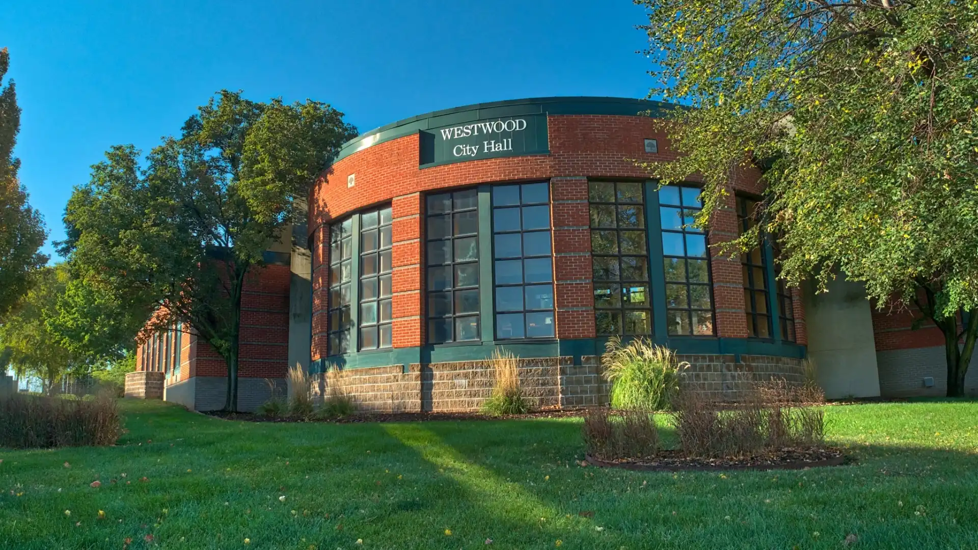 Westwood City Hall, a curved red brick building with tall green-framed windows