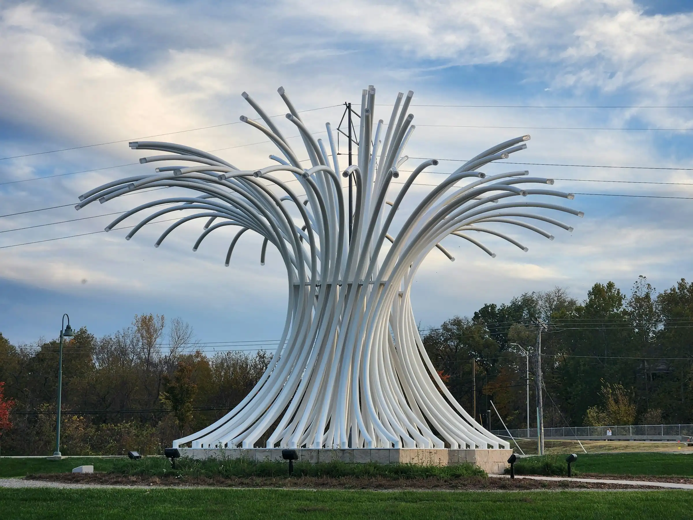Large white curved-tube public sculpture standing in a Leawood, Kansas park