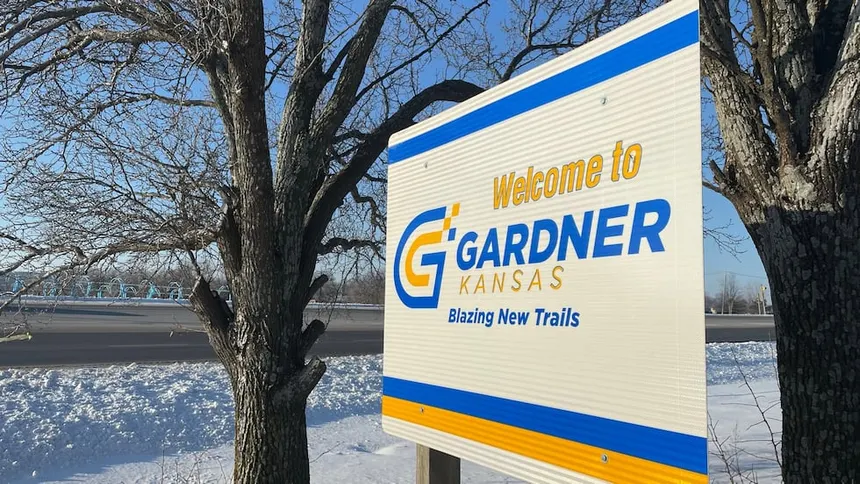 "Welcome to Gardner, Kansas - Blazing New Trails" sign between bare trees on a snowy roadside