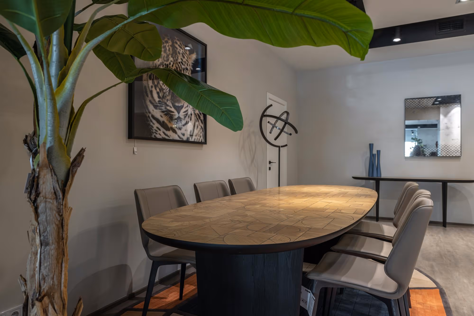 Modern dining room with a patterned wooden table, leather chairs, and a large plant