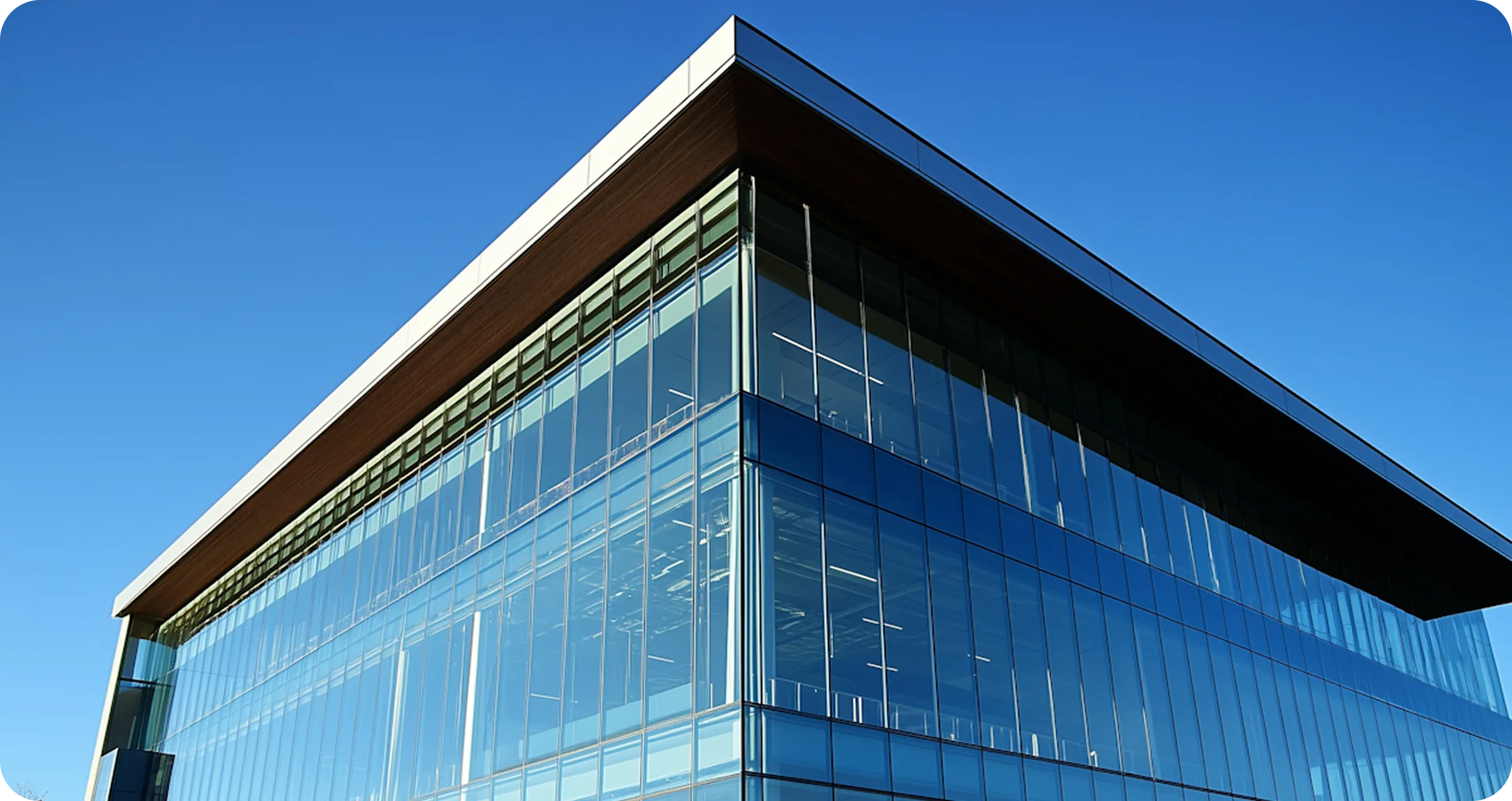 Modern glass office building with clear blue sky background.