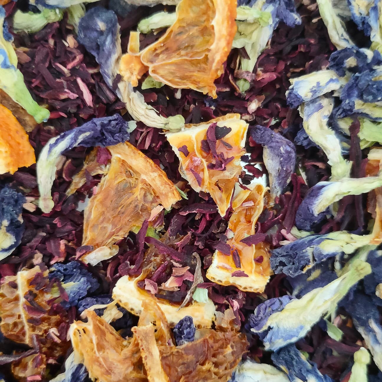 Close-up of the loose blend: dark red hibiscus, dried orange slices and blue butterfly pea petals.